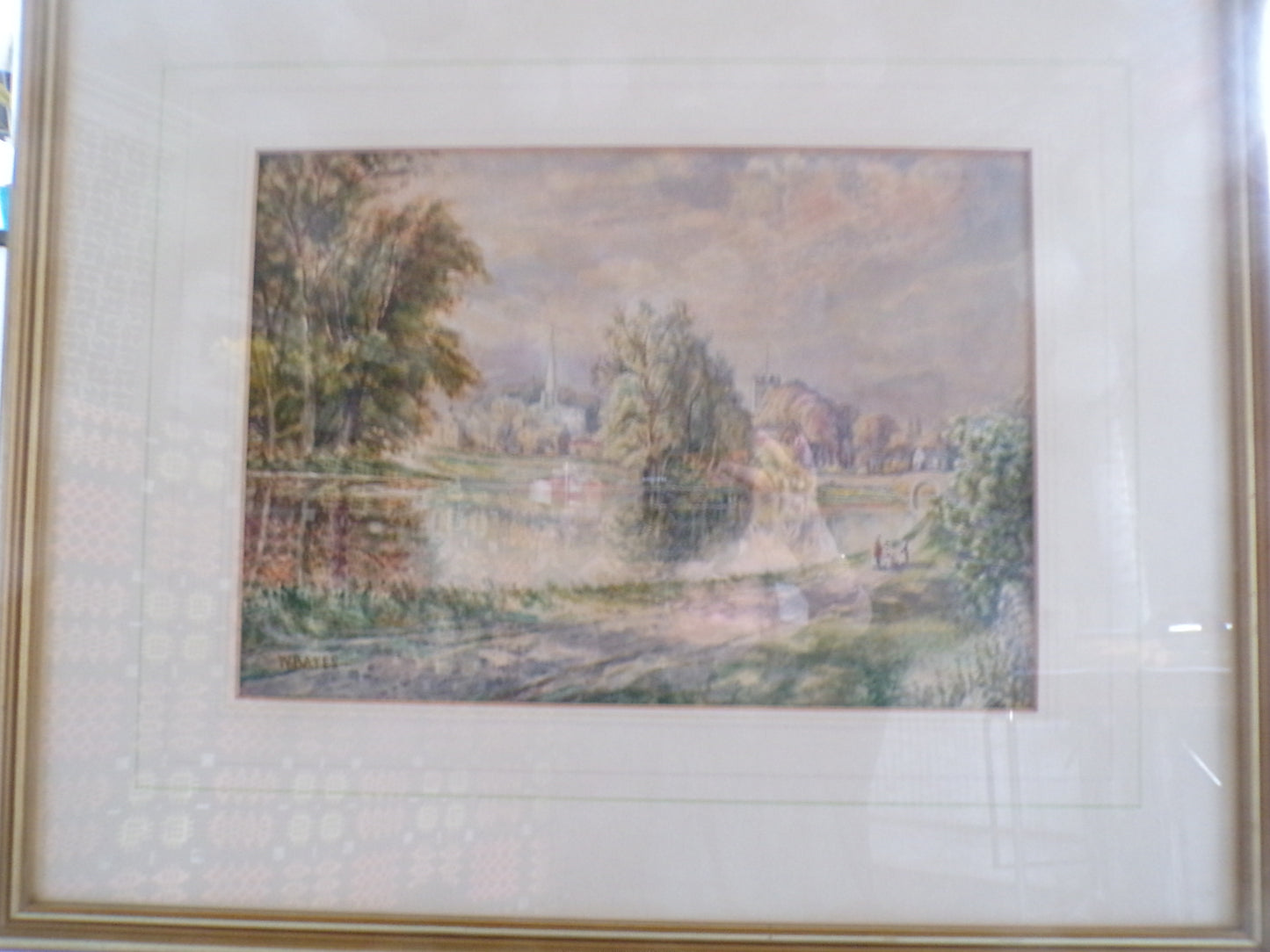 Framed W Bates watercolour of a lake and town scene.