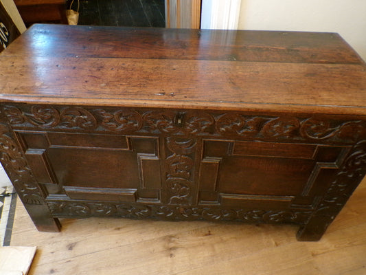 Seventeenth Century oak coffer with tulip and leafage carving surrounding two geometric mouldedpanels.