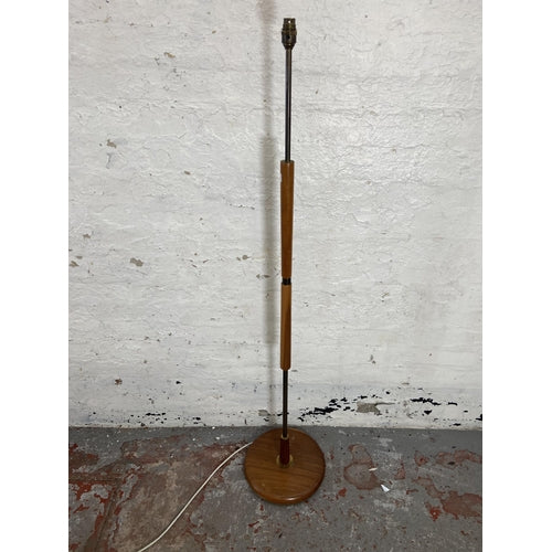 A pair of mid-century teak and brass standard lamp with circular base